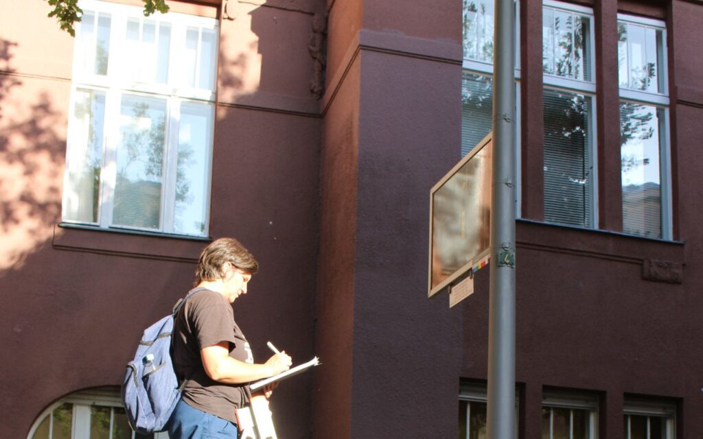 Tine Lippert erstellt Konzepte & Beratung: Sie begutachtet eine historisches Schild und macht sich Notizen auf einem Klemmbrett.
