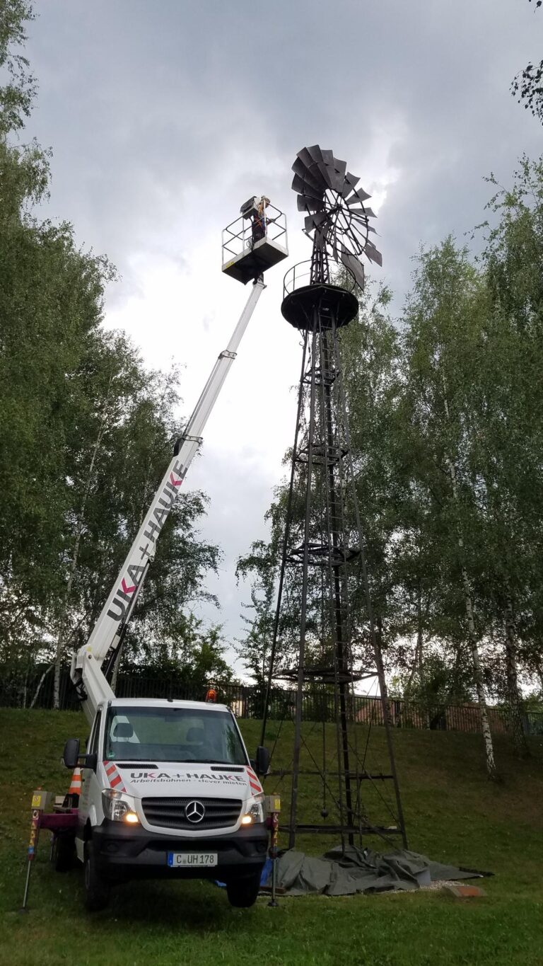 Ein historisches Windrad in Chemnitz, an dem ein Korrosionsschutz für das Denkmal von einem Hubsteiger aus aufgetragen wird.