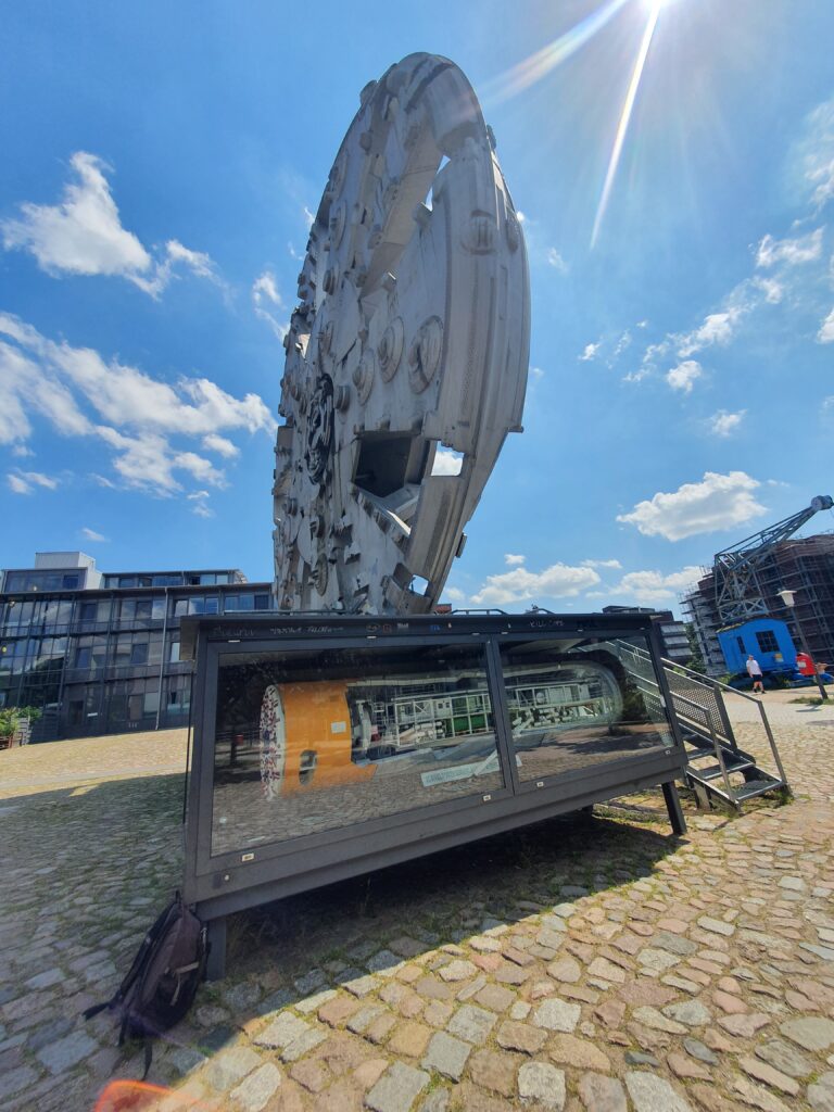 Das restaurierte Modell der TRUDE Tunnelbohrmaschine in seiner Vitrine vor dem riesigen Original-Schneidrad.